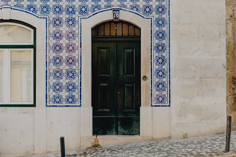 Husfasad klädd i blå azulejos med en mörkgrön ytterdörr